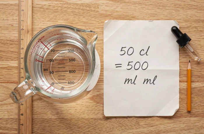 Vue aérienne d'un pichet gradué à 500 ml avec une fiche manuscrite indiquant la conversion 50 cl en millilitres