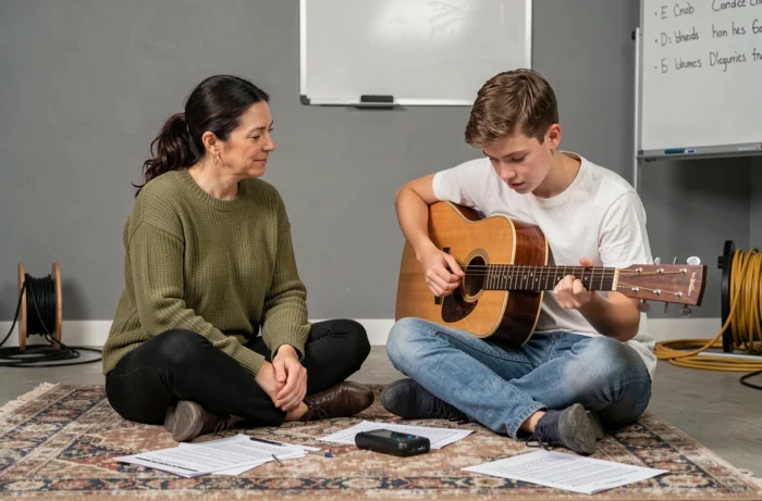 Duo mère et fils en session de répétition musicale informelle avec guitare acoustique et partitions sur le sol